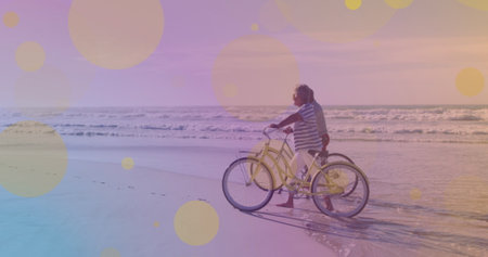 Yellow spots of light against african american senior couple with bicycles walking together at...