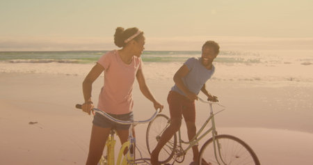 Spots of light against african american couple riding bicycles together at the beach. pedal day...