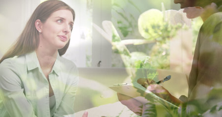 Image of plants over caucasian woman consulting psychologist. Mental health, therapy and healthcare concept digitally generated image.の写真素材