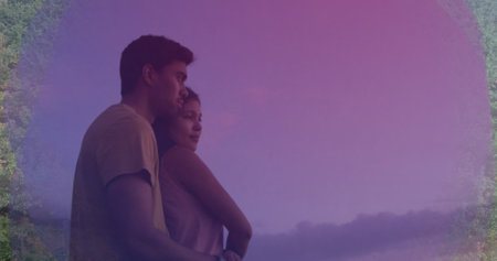 Diverse couple embracing, looking into distance. both wearing casual clothes, sharing quiet moment together, surrounded by a dreamy purple hazeの写真素材