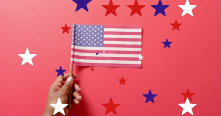 Image of stars falling over hand holding flag of united states of america on red background. American independence, tradition and celebration concept digitally generated image.の写真素材