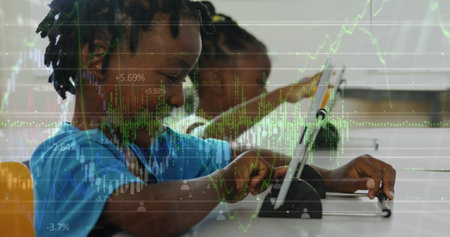 Two African American friends, one male and one female, are focusing on tablet. Both have dark hair, girl wearing a blue shirt, the boy in yellowの写真素材