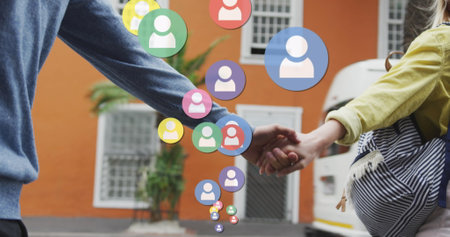 Image of social media icons floating over caucasian couple walking and holding hands. social media...