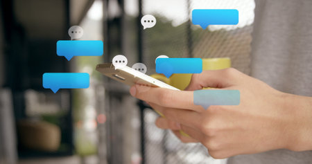 Multiple speech bubbles floating against mid section of caucasian woman using smartphone. Social...