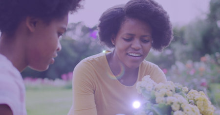 Spot of light against african american mother and daughter gardening together in the garden. community garden week awareness conceptの写真素材