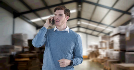 Image of man talking on smartphone with stacks of boxes in warehouse. global shipping and technology concept digitally generated image.の写真素材