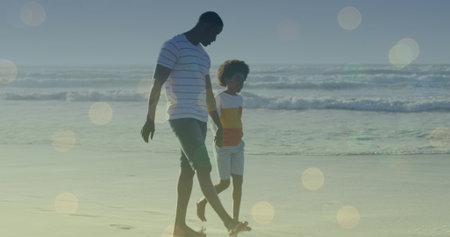 Image of light spots over african american man and his son walking together. walk day and celebration concept digitally generated image.の写真素材