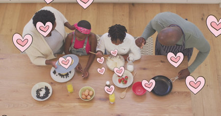 Image of pink hearts over happy african american grandparents and grandchildren cooking at home. family, togetherness and wellbeing concept digitally generated image.の写真素材