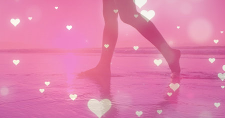 Multiple glowing heart icons falling against low section of a woman walking on the beach. Love and relationship conceptの写真素材