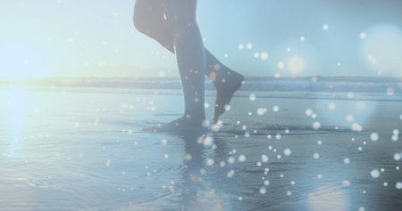 Glowing blue spots of light against low section of a woman walking on the beach. Love and relationship conceptの写真素材