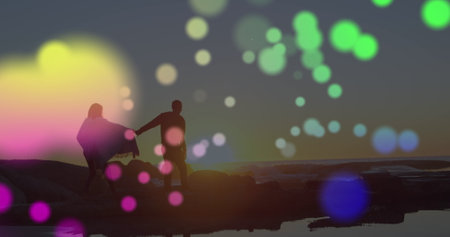 Colorful spot of light over african american couple holding hands walking on the rocks near the sea. Love and relationship conceptの写真素材