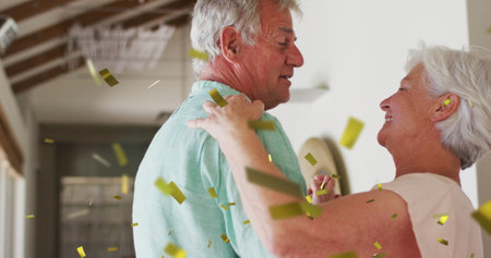 Image of gold confetti falling over happy caucasian senior couple dancing at home. retirement...