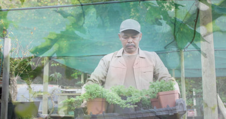 Image of blue lights over biracial man working in the garden. community garden week digitally generated image.の写真素材