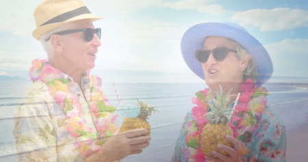 Image of glowing light over happy senior couple having cocktails by seaside. retirement and senior life concept digitally generated image.の写真素材