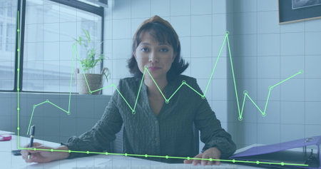 Image of financial data processing over asian businesswoman working at office. Global business, finances and digital interface concept digitally generated image.の写真素材