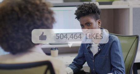 Image of like icon with growing number over diverse business people working at office. Global...