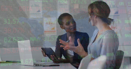 Image of financial data and graphs over diverse female coworkers in office. Business, finance, economy and cooperation concept digitally generated image.の写真素材