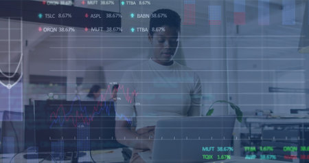 Image of financial data and graphs over african american woman with laptop in office. Business,...
