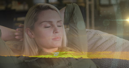 Image of plants over smiling caucasian woman relaxing on couch. Healthy lifestyle, relaxation and tranquility concept digitally generated image.の写真素材