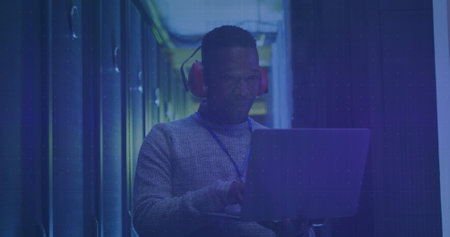 Image of financial data processing over african american man in server room. global finance,...