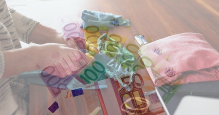 Image of Euro bills lying on a table over Caucasian woman sewing face masks. Coronavirus Covid-19 concept digital compositionの写真素材
