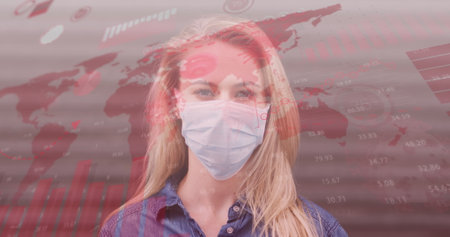 Image of world map and statistic data over caucasian female wearing face mask. global covid 19 pandemic, health and science concept digitally generated image.の写真素材