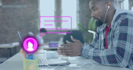 Image of media icons over african american businessman using laptop in office. Global business,...