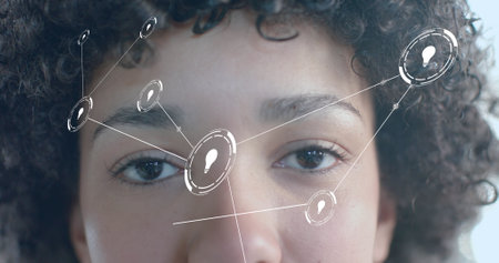 Image of lightbulb icons over biracial businesswoman in office. Global business, technology and digital interface concept digitally generated image.の写真素材