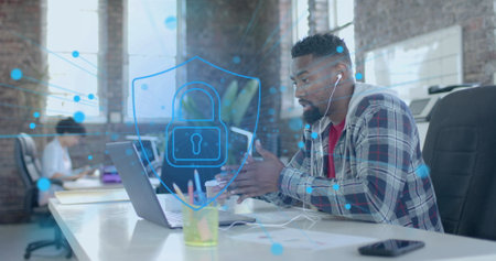 Image of padlock and spots over african american businessman using laptop in office. Global...