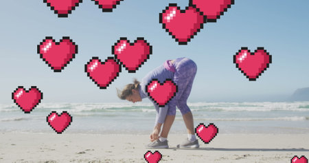 Image of floating red pixel hearts, over woman tying shoe on beach. positive feelings and wellbeing...