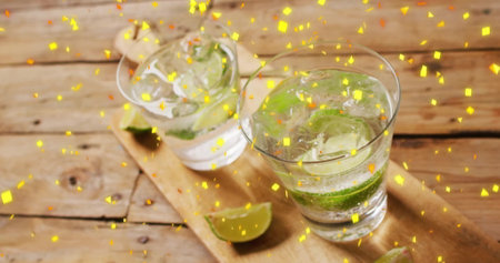 Image of confetti falling and cocktails on wooden background. Party, drink, entertainment and...
