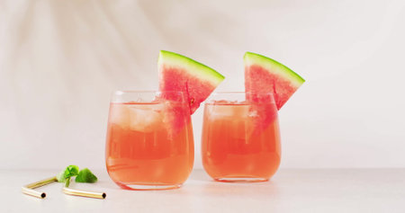 Two glasses of watermelon juice are on display, with copy space. Refreshing summer drinks with a slice of watermelon add a vibrant touch to the setting.の写真素材
