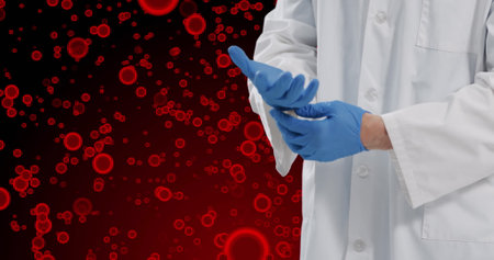 Image of midsection of caucasian male doctor with glove over red cells on red background. Human biology, anatomy and medicine concept digitally generated image.の写真素材