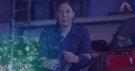 Image of glowing lights over caucasian female car mechanic in workshop. labor day, work, workers,...