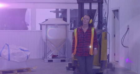 Image of glowing light over caucasian woman working in warehouse. labor day, work, workers, tradition and celebration concept digitally generated image.の写真素材