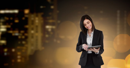 Image of businesswoman using digital tablet over glowing spots of light and cityscape. global business, finances and technology concept digitally generated image.の写真素材