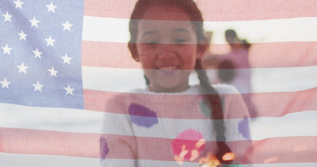 Biracial girl smiles behind a translucent American flag. The flag overlay symbolizes cultural...