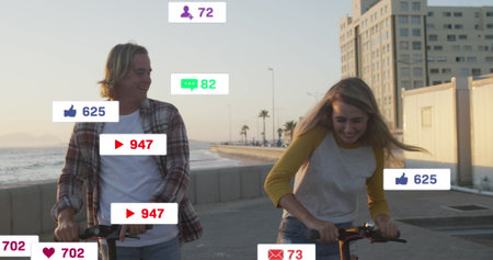 Image of social media icons on banners over happy caucasian couple on scooters by seaside. social...