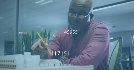 Image of numbers and data processing over african american businessman working in office. Global...