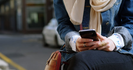 Image of smiling asian woman in hijab with smartphone over cityscape. out and about in the city,...