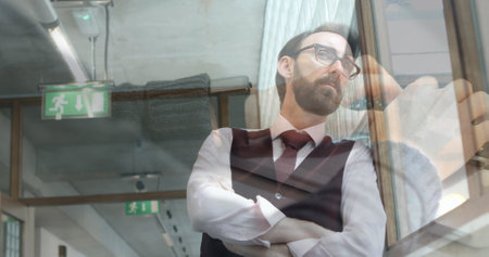 Image of hands using laptop over businessman looking out of window at office. business and...