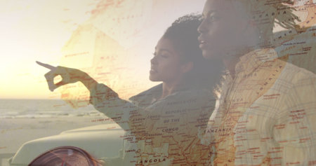 Image of happy african american couple enjoying sunset view at beach over world map. nature, happy holidays and summer, digitally generated image.の写真素材