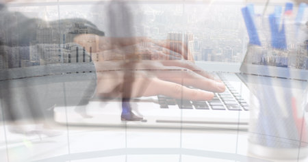 Image of hands working on laptop over sped up commuters walking in modern building. business and communication technology concept digitally generated image.の写真素材