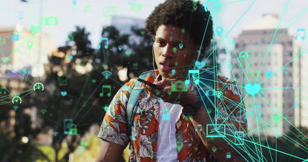 Image of media icons over african american man using smartphone. Global business and digital interface concept digitally generated image.の写真素材