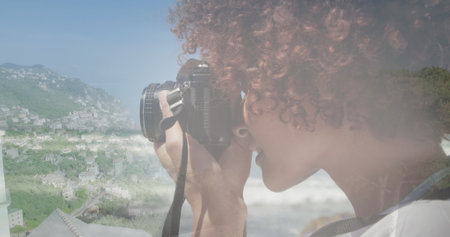 Image of african american woman using camera, over cityscape. happy holidays and free time digitally generated image.の写真素材