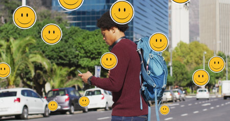 Image of emoji icons over african american man using smartphone. Global business and digital interface concept digitally generated image.の写真素材