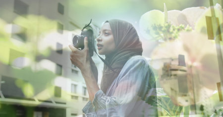Image of asian woman in hijab with camera over cityscape. out and about in the city, digitally generated image.の写真素材