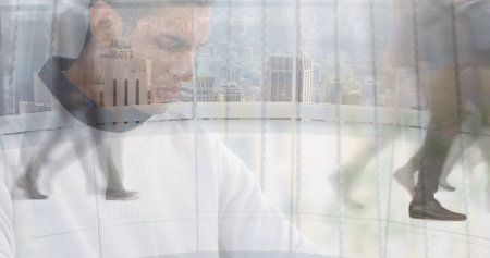 Image of man working on laptop over sped up commuters walking in modern building. business and communication technology concept digitally generated image.の写真素材