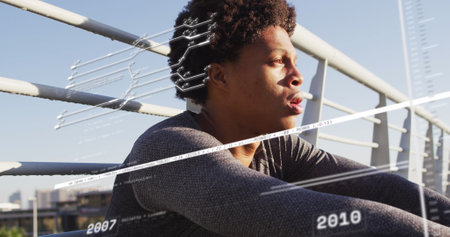 Image of data processing over african american man sitting. Global business and digital interface concept digitally generated image.の写真素材