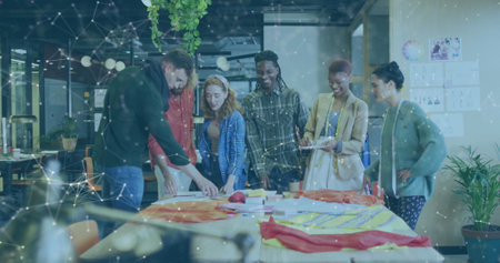 Diverse group of young professionals collaborate in an office. They engage in a creative brainstorming session around a table with materials.の写真素材